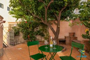 einen Tisch und Stühle mit Weingläsern und einem Baum in der Unterkunft Verosicily Ottaviano House in Taormina