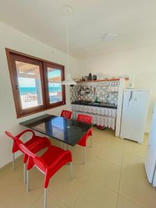cocina con mesa, sillas rojas y nevera en URUAÚ BEACH RESIDENCE, en Beberibe
