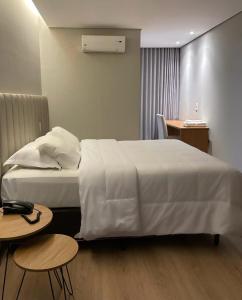 a hotel room with a white bed and two tables at Ouro Cerrado Palace Hotel in Patrocínio