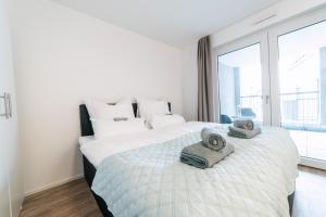 een witte slaapkamer met een groot bed met handdoeken erop bij ZENtrahome - Zentral Outlet Business SmartTV Balkon in Metzingen