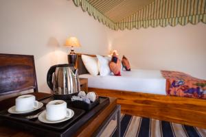 Sonal Desert Camp Jaisalmer في جيلسامر: غرفة نوم بسرير وطاولة مع جهاز صنع القهوة