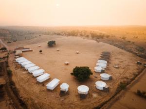 Sonal Desert Camp Jaisalmer في جيلسامر: مجموعة مظلات بيضاء على ارض ترابية