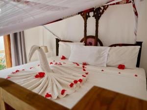 a white bed with a white swan with red roses on it at Nungwi ocean view in Nungwi