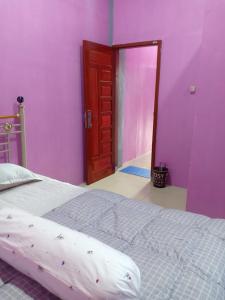 1 dormitorio con paredes moradas, 1 cama y puerta en D' pamor Homestay, en Halangan