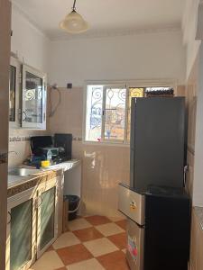 uma cozinha com um frigorífico preto e piso em azulejo em Olas Surf House em Imsouane