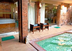 un porche con 2 sillas y una piscina en Southern Bali Villa en Nusa Dua
