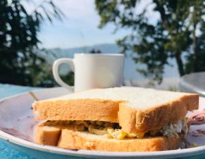un panino su un piatto con una tazza di caffè di Hom's Homestay & Farmstay Sarangkot Pokhara a Pokhara