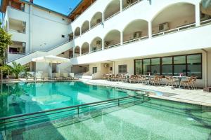 a large swimming pool in a building with tables and chairs at Elinotel Polis Hotel in Hanioti