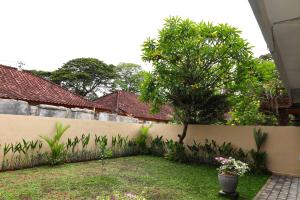 een achtertuin met een hek en een boom bij Pondok Dete Guesthouse in Sanur