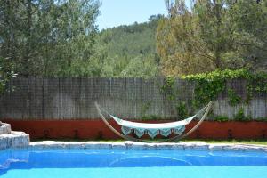 a hammock in front of a fence next to a swimming pool at Villa Sitges El Olivo High Comodity AC Pool Heated 30º Optional Real Garden Pool XXL 10 min drive from Sitges in Olivella
