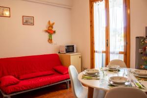 salon z czerwoną kanapą i stołem w obiekcie Piscina e Posto Auto per un Relax a 400 mt dal mare w mieście Pietra Ligure