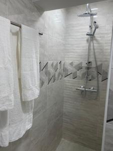 uma casa de banho com um chuveiro e toalhas brancas em Мотел Тихия кът em Sófia