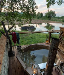 a hot tub on a deck with a view of a pond at Jaci's Lodges in Madikwe Game Reserve