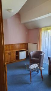 a living room with a chair and a coffee table at Atryum Hotel és Panzió in Szolnok