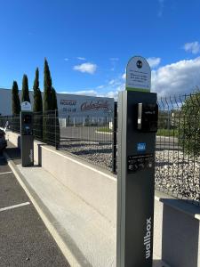 um parquímetro num parque de estacionamento ao lado de uma cerca em B&B HOTEL Montélimar Sud em Montélimar