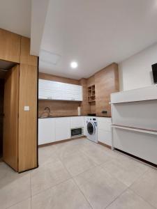 a kitchen with white cabinets and a washer and dryer at Apartment ARSO in Velenje