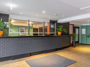 a lobby with a brick counter with potted plants at Good Morning + Berlin City East in Berlin