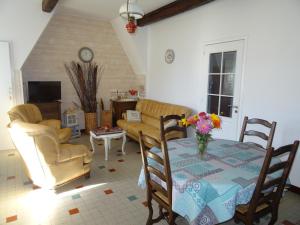a living room with a table and chairs and a couch at Le Clos Fleuri in Caumont