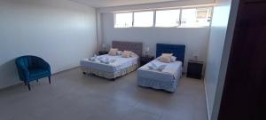 a room with two beds and a chair and a window at Mantarraya in Puerto Baquerizo Moreno