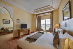 タンジェにあるグランド モガドール シー ビュー ＆ スパの大型ベッドとテレビが備わるホテルルームです。