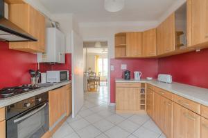 - une cuisine avec des placards en bois et un mur rouge dans l'établissement Le Parilly - Ma Cabotte, à Vénissieux