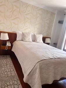 a bedroom with a large bed and two lamps at VIRREYES HOTEL in Potosí