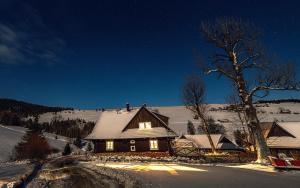 a house is covered in snow at night at Drevenica Spiaci Goral in Ždiar