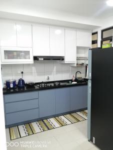 a kitchen with white cabinets and a black refrigerator at KASTURI GUEST HOUSE PUTRAJAYA in Putrajaya