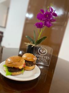 a plate with a hamburger and a vase with purple flowers at VIRREYES HOTEL in Potosí