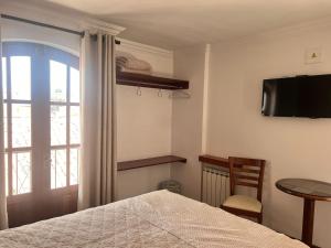 a bedroom with a bed and a tv and a window at VIRREYES HOTEL in Potosí