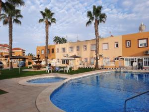 a pool in front of a building with palm trees at Casa Pelican in Orihuela Costa