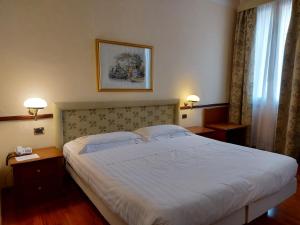 Phi Hotel Dei Medaglioni في كوريدجو: غرفة نوم بسرير كبير ومصباحين