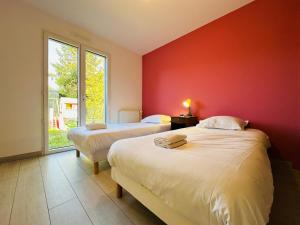two beds in a room with a red wall at La maison de Rochefuret in Ballan-Miré