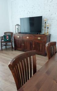 uma televisão sentada num centro de entretenimento de madeira com duas cadeiras em Apartament z Napoleonem w tle em Lidzbark Warmiński