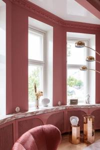 - un salon avec des murs rouges, des fenêtres et une chaise dans l'établissement Luxury Pink Suite, à Helsinki