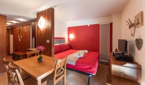 Sala de estar con cama roja y mesa en Chalet della Neve - Ski Access-Parking-Wifi, en Limone Piemonte