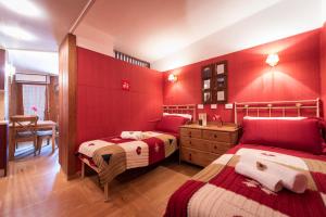 2 camas en una habitación con paredes rojas en Chalet della Neve - Ski Access-Parking-Wifi, en Limone Piemonte