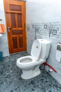 baño con aseo y puerta de madera en Kavi Villa, en Bentota