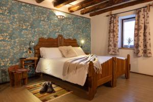 1 dormitorio con cama de madera y papel pintado con motivos florales en Chalet d'Aoste, en Aosta