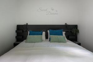 een bed met blauwe en groene kussens erop bij Lodge Vlinder Nunspeet Veluwe in Nunspeet