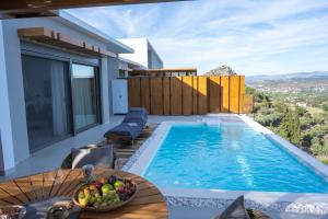 a pool with a table and a bowl of fruit next to a house at AZIZA luxury suite in Tolo