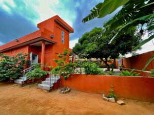un edificio rojo con una escalera delante en Les Amazones Rouges Chambre Verte en Ouidah