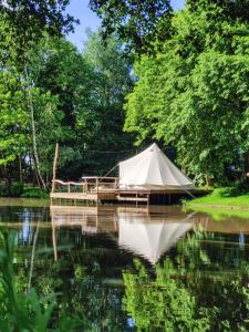 une tente blanche assise sur l'eau à côté d'un quai dans l'établissement POLE POLE - Ijsbeer, à Lichtaert