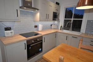 a kitchen with white cabinets and a sink and a table at Delightful Cottage in Sandwich - One Bedroom in Sandwich