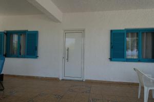 a room with blue shutters and a door and a chair at Studio in Villa in Kalloni direkt am Meer in Kalloni