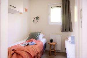 um pequeno quarto com uma cama e uma janela em Lodge Steltloper Nunspeet Veluwe em Nunspeet