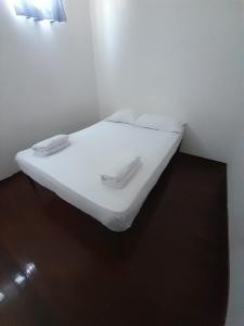 ein weißes Bett in einem weißen Zimmer mit 2 Handtüchern in der Unterkunft Apartamento Amoblado con Ventilador in Montería