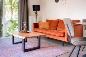 een woonkamer met een oranje bank en een tafel bij Lodge Steltloper Nunspeet Veluwe in Nunspeet