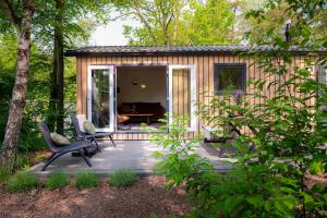 a tiny house with a patio in the woods at Lodge Steltloper Nunspeet Veluwe in Nunspeet
