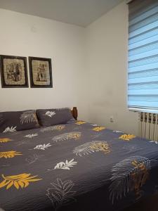 a bed with a blue blanket with flowers on it at Apartment Green Free private parking in Novi Sad